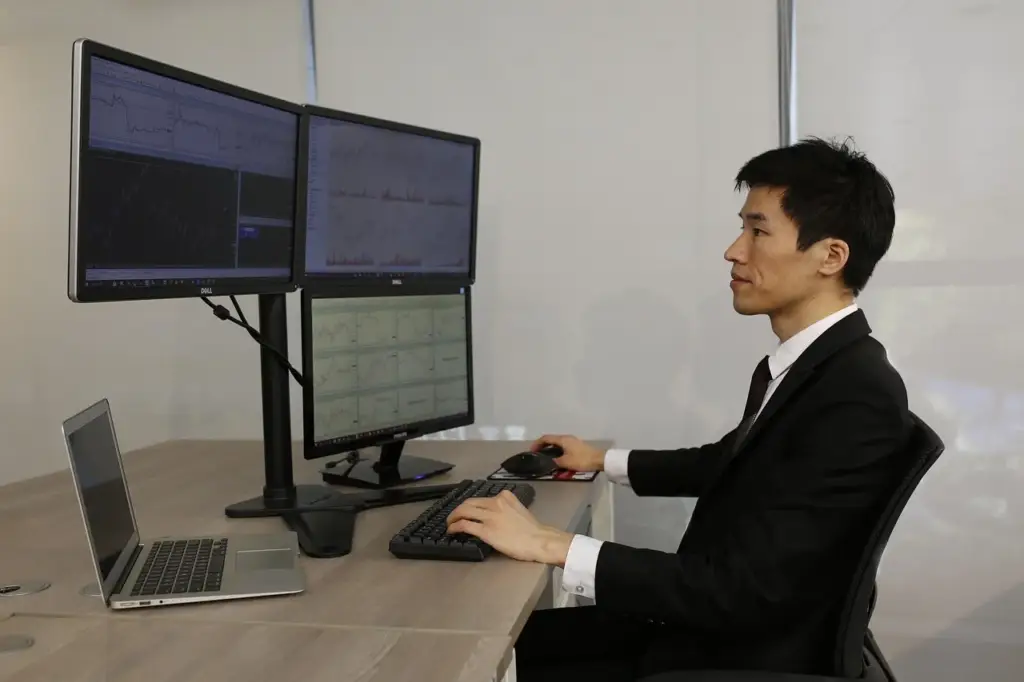 Trader at desk with multiple screens for forex arbitrage