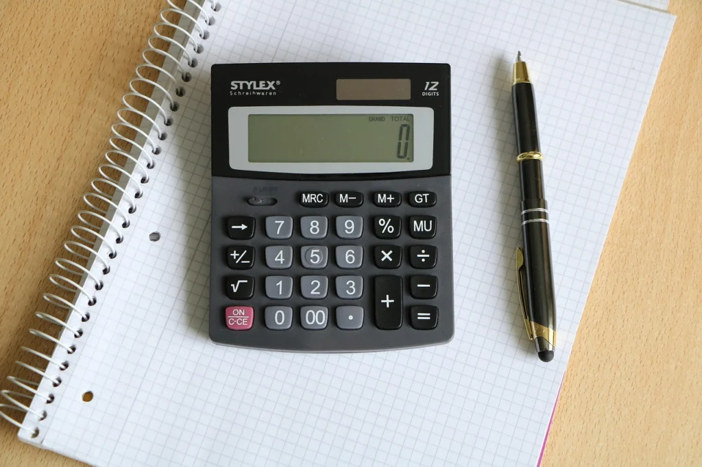 Calculator and laptop used to calculate crypto arbitrage fees