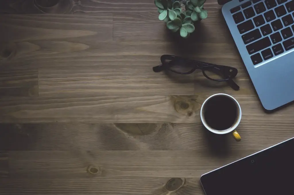 Laptop with cryptocurrency charts and a coffee cup on a desk, representing manual trading